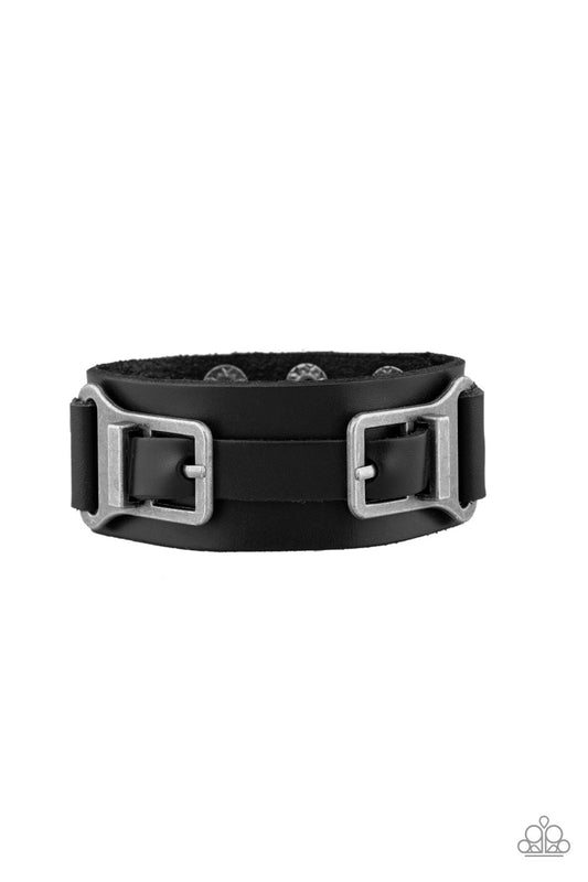 A collection of leather pieces and antiqued gunmetal frames are studded in place across the front of a thick leather band, creating an abstract buckle. Features an adjustable snap closure.  Sold as one individual bracelet.