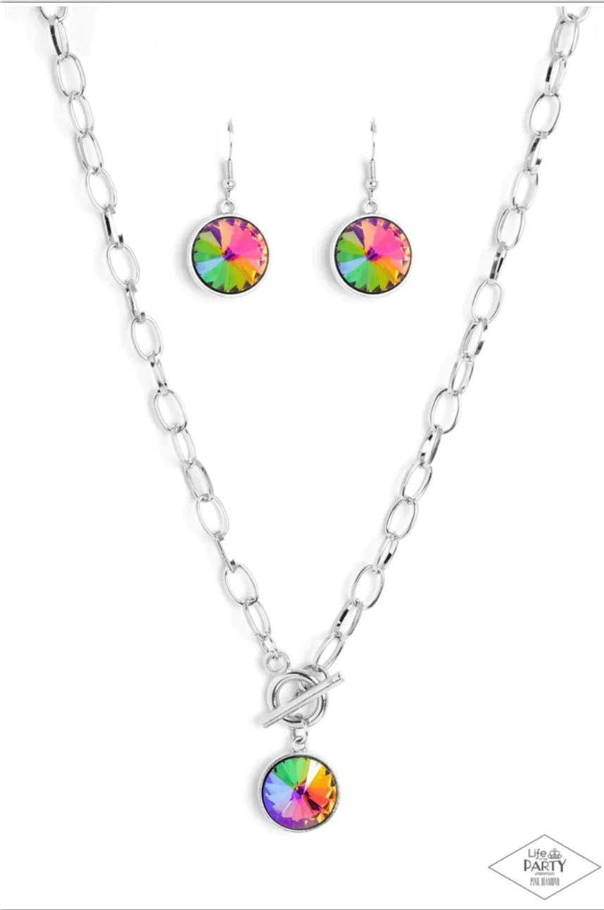A dramatic gem with a UV shimmer swings from the bottom of a shiny silver chain, creating a blinding pendant below the collar. Features a toggle closure. Due to its prismatic palette, color may vary.  Sold as one individual necklace. Includes one pair of matching earrings.