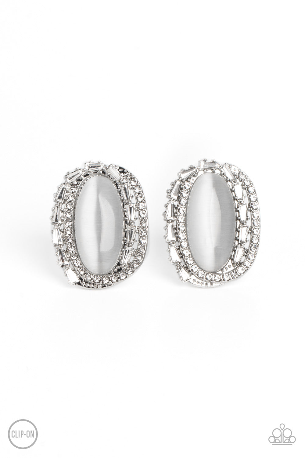 Rows of white rhinestones, silver studs, and white gem bars create dramatic dimension encircling an elongated white cat's eye stone for a sparkly statement piece. Earring attaches to a standard clip-on fitting.  Sold as one pair of clip-on earrings.