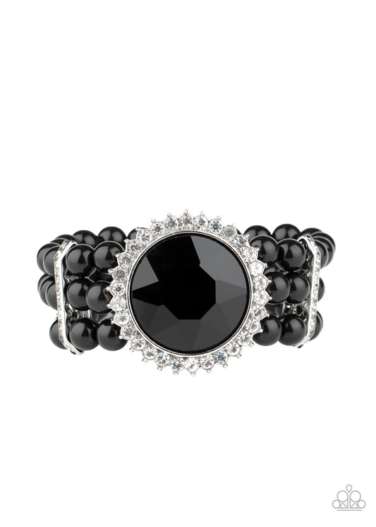 Threaded along stretchy bands, strands of polished black beads are held in place with white rhinestone encrusted fittings around the wrist. Bedazzled in a ring of glassy white rhinestones, a dramatically oversized black gem adorns the center for a speechless finish.  Sold as one individual bracelet.