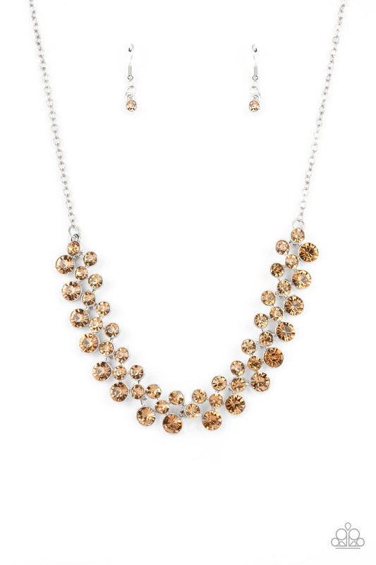 Encased in sleek silver frames, staggered rows of bubbly golden topaz rhinestones effervescently link below the collar for a glamorous pop of sparkle. Features an adjustable clasp closure.  Sold as one individual necklace. Includes one pair of matching earrings.